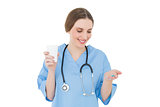 Female doctor holding a plastic cup and blue pills while looking on them