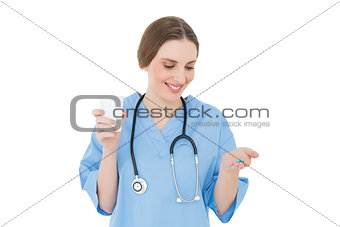 Female doctor holding a plastic cup and blue pills while looking on them