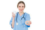 Female doctor holding a plastic cup and handing blue pills