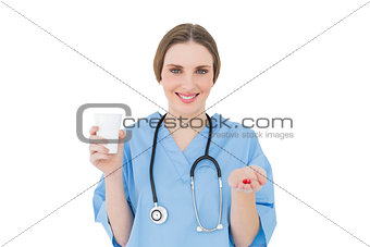 Female doctor holding a plastic cup and red pills