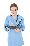 Smiling female doctor writing into a file