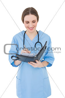 Smiling female doctor writing into a file