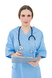 Young female doctor working with her clipboard and looking into the camera