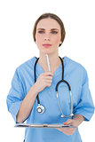 Thinking female doctor holding a clipboard