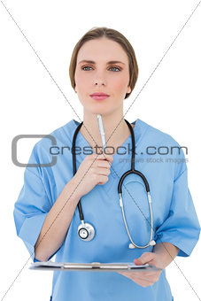 Thinking female doctor holding a clipboard