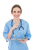 Thinking female doctor keeping a clipboard smiling into the camera