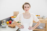 Serious brunette woman posing in kitchen with hands on hips