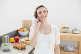 Happy cute woman phoning standing in her kitchen