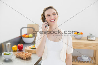 Happy cute woman phoning standing in her kitchen