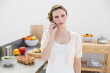Young woman standing in kitchen while phoning