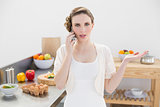 Attractive young woman discussing on the phone standing in the kitchen