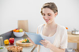 Content smiling woman working with her tablet in kitchen