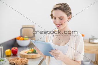 Content smiling woman working with her tablet in kitchen