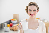 Cheerful lovely woman standing in her kitchen holding a cup