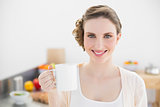 Peaceful young woman standing in her kitchen holding a cup