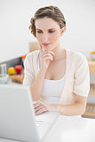 Attractive calm woman sitting thoughtful in front of her laptop