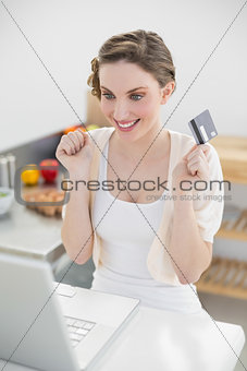 Cheerful attractive woman home-shopping with her notebook