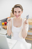 Happy brunette woman sitting in kitchen while home shopping