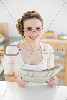 Young woman wearing glasses for reading newspaper in her kitchen