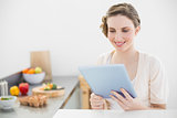 Content peaceful woman using her tablet sitting in her kitchen