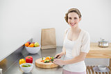 Cute woman cutting vegetables standing in her kitchen