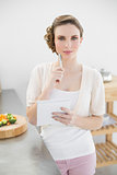 Beautiful thinking woman writing a shopping list standing in kitchen