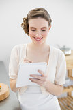 Content lovely woman standing in her kitchen writing a shopping list