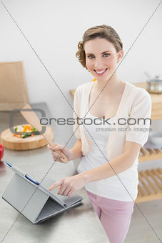 Content woman working with her tablet standing in the kitchen