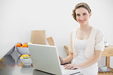 Cheerful beautiful woman using her laptop standing in her kitchen