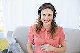 Happy beautiful pregnant woman relaxing in the living room listening to music