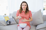 Young pregnant woman watching television sitting on couch