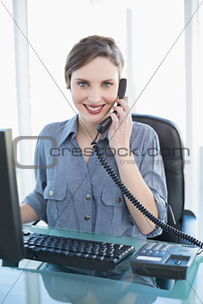Casual pretty businesswoman phoning with telephone at desk