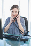 Cute young businesswoman phoning with telephone sitting at desk