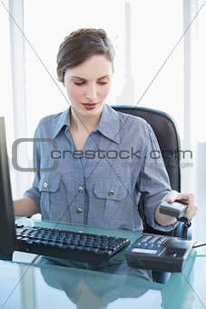 Attractive calm businesswoman hanging up the telephone