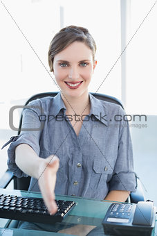 Friendly businesswoman welcoming while sitting at her desk