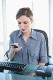 Young businesswoman using her smartphone sitting at her desk