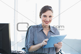 Portrait of attractive young businesswoman using her tablet sitting at her desk