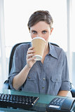 Businesswoman drinking of disposable cup sitting at her desk