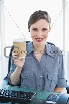 Cheerful young businesswoman presenting disposable cup