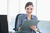 Portrait of beautiful businesswoman holding a clipboard sitting at her desk