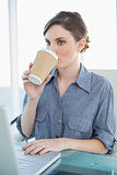Beautiful businesswoman drinking of disposable cup sitting at her desk