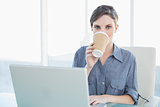 Gorgeous young businesswoman drinking from disposable cup