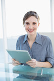 Beautiful businesswoman holding her tablet sitting at her desk