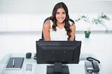 Smiling cute businesswoman sitting behind desk