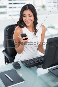 Smiling cute businesswoman holding smartphone