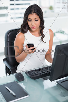 Frowning cute businesswoman holding smartphone