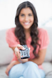 Happy cute brunette sitting on couch holding remote