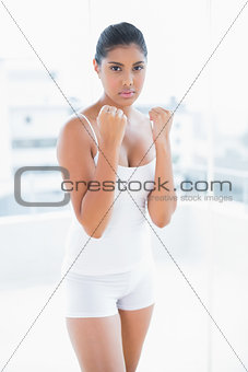 Serious toned brunette standing with lifted fists