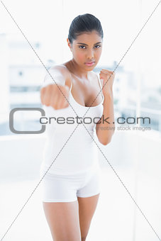 Serious toned brunette boxing towards camera