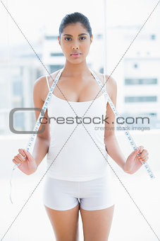 Serious toned brunette holding measuring tape